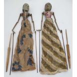 A pair of mid 20thC Indonesian carved wooden stick puppets in traditional dress.