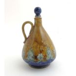 A Royal Doulton Lambeth decanter and stopper painted in a raw sienna colour and decorated with blue