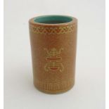 A Chinese brush pot of cylindrical form in burnt orange with gilt coloured highlights,