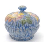 A hand painted lidded glass powder bowl decorated in polychrome with roses and foliage on a blue