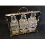 An early 20thC silver plate Tantalus / decanter stand (locked) with 3 glass decanters.