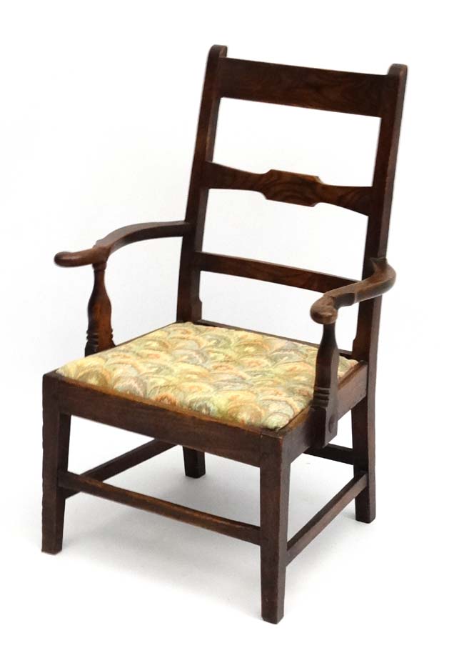 An early 19thC elm country made open armchair with drop in seat and squared tapering legs.