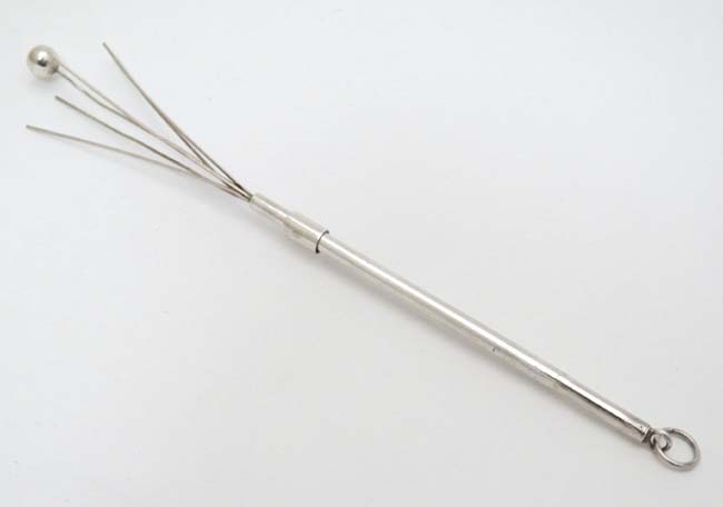 A silver and white metal swizzle stick 3 1/4" long (closed) CONDITION: Please Note