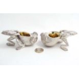 A pair of novelty silver plate table salts formed as frogs with shells.