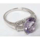 A 9k white gold ring set with central amethyst flanked by white stones.