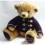 A Harrods millennial brown Christmas teddy bear wearing a purple coat, with foot dated 2000,