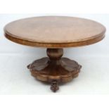 An early Victorian mahogany circular tilt top pedestal breakfast table having lions paw feet and a