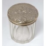 A cut glass dressing table jar with silver top having embossed cherub decoration.