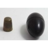 A turned wooden thimble case of egg form with brass thimble.