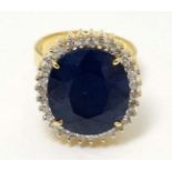 A 14ct gold ring set with large semi precious blue stone bordered by diamond.