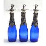 Three 21st C blue glass decanters / carafes with silver plate grape and vine decoration.