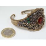 A white and gilt metal bracelet set with various red, purple, green and white stones.