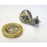 A silver miniature model of a snail, the shell hinging open to form a pill box.