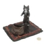 A 21st C Cold painted novelty bronze inkwell of a cat on carpet with satchel.