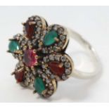 A white metal ring set with red green and white stones.