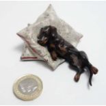 A novelty cold painted bronze figure formed as a dachshund/sausage dog on pillow. 21st C.