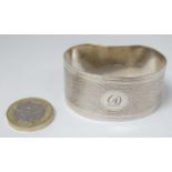 A silver napkin ring of shaped form with engine turned decoration.