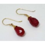 A pair of gold drop earrings set with facet cut red stone drops.