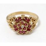 A 14ct gold ring set with central diamond bordered by rubies in a floral setting