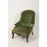 A VICTORIAN WALNUT FRAMED BUTTON BACK ARMCHAIR upholstered in green with scrolling carved arm