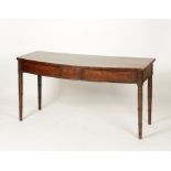 A GEORGE III MAHOGANY BOW FRONT SERVING TABLE, the shaped top above a conforming frieze with central