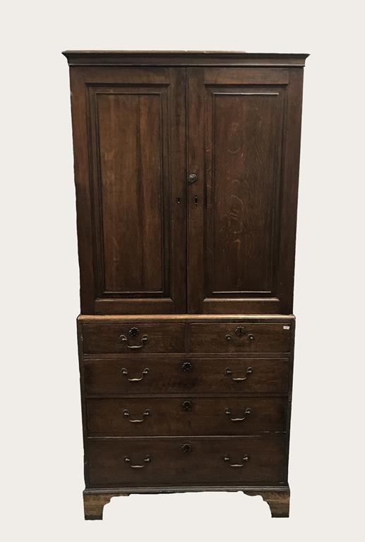 AN OAK PRESS OR HOUSEKEEPERS CUPBOARD, the top with two panelled doors enclosing a shelved interior,