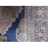 A LARGE PERSIAN STYLE CARPET worked with a central medallion in pale reds and blues against a deep