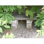 A RECONSTITUTED STONE GARDEN BENCH, the rectangular top with a moulded border on twin corbel type