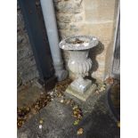 A SMALL RECONSTITUTED STONE GARDEN URN of flared circular form, with lobed body on a square base,