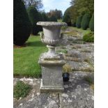 A PAIR OF RECONSTITUTED STONE GARDEN URNS of traditional twin handles and lobed bases, on square