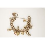 A 9CT YELLOW GOLD CURB LINK CHARM BRACELET