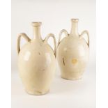 A PAIR OF CREAM GLAZED TWIN HANDLED PORTUGUESE POTTERY VASES