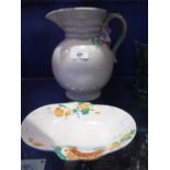 A CLARICE CLIFF POTTERY JUG with moulded and floral mounted handle and a similar shallow dish