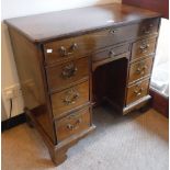 A GEORGE III MAHOGANY KNEEHOLE DESK with an arrangement of drawers and a recessed cupboard on