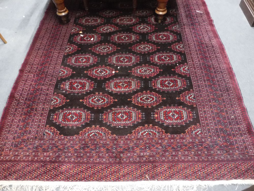 A MODERN FINE WEAVE BOKHARA TYPE RUG of traditional design on a dark ground, approx. 73" x 107"