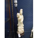 A 'JADE' FIGURE OF AN ORIENTAL DEITY standing on a carved wooden base, fitted as a table lamp