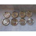 A SET OF EIGHT SILVER DISHES, the bases inlaid with One Rupee, Indian Coins, two dated 1916, three