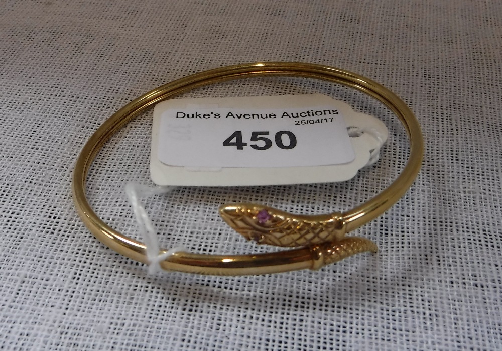 A 9CT YELLOW GOLD SERPENT BANGLE, inset with pale ruby eyes