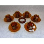 A SET OF SIX AMBER GLASS CUPS AND SAUCERS and a bead bracelet