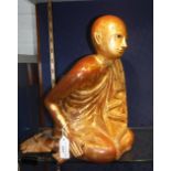 AN EASTERN CARVED WOOD AND BROWN/GILT PAINTED FIGURE of a kneeling Buddha, 12.5" high