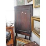 A GEORGE II OAK HANGING CORNER CUPBOARD with fielded panel door, 'H' hinges and later stand
