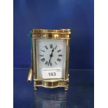 AN EDWARDIAN BRASS-CASED CARRIAGE CLOCK with bevelled glass panels and enamel dial, 4.5" high