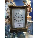 A BRASS CARRIAGE CLOCK with bevelled glass panels and enamel dials, 4.5" high