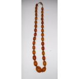 A GRADUATED 'AMBER' BEADED NECKLACE on a chain, the clasp marked 14ct GS