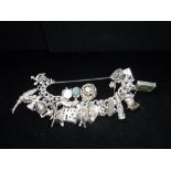 A SILVER CHARM BRACELET decorated with multiple charms including silver violin, and old style £10