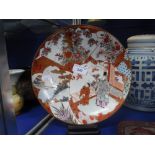 A JAPANESE PORCELAIN KUTANI PLATE decorated with a Sage and young woman in a garden with flowers and