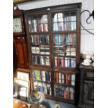 A 1920S OAK BOOKCASE with leaded glass doors and carved grotesque decoration, 43" wide