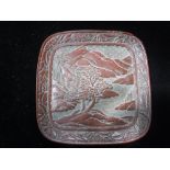 A CHINESE RED LACQUER DISH of shaped square form, decorated with a house and trees in a