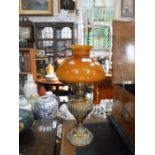 AN EDWARDIAN EMBOSSED BRASS OIL LAMP with a burnt orange glass shade