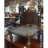 A LOW SEATED TRIBAL CHAIR with carved decoration and woven seat